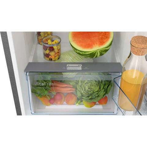 Open Bosch refrigerator door showing a VitaFresh food storage container with fruits and vegetables inside.